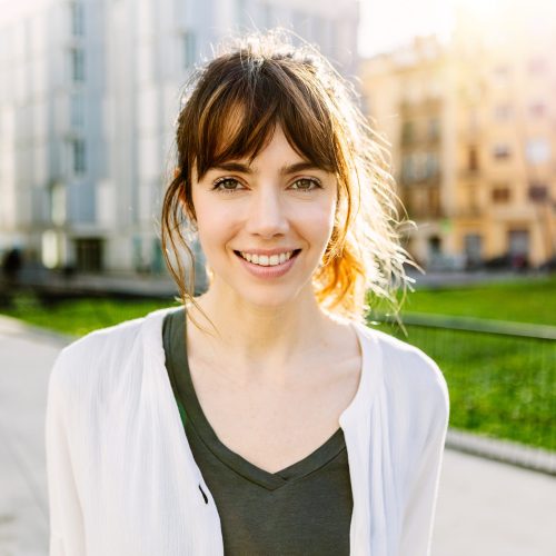 Outdoors portrait of beautiful young girl smile at camera over urban city background