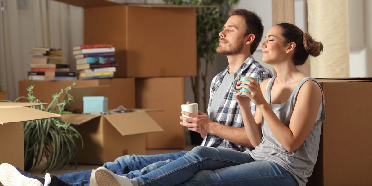 Happy couple moving home resting breathing fresh air sitting on the floor holding coffee cups